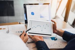 Business partnership coworkers using a tablet to chart company financial statements report and profits work progress and planning in office room. photo