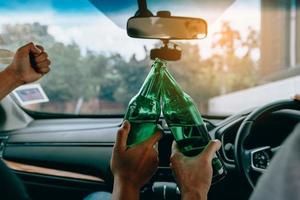 Two male friends are celebrating in the car while they are clinking beer bottle together. photo