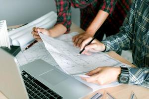 Architects working with blueprints and discussing project together at the meeting in the office. photo