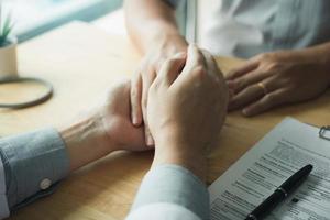 Doctor holds hands and leaves comforting counselors to patient. photo