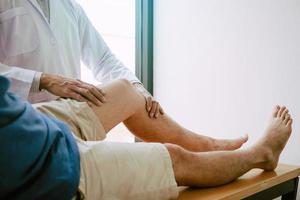 los fisioterapeutas están usando el mango en la rodilla del paciente para comprobar si hay dolor.