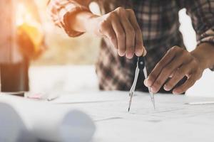 Close up of an architect's hands using a drawing compass on a blueprint. photo