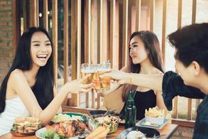 grupo de asiáticos animando cerveza en el restaurante happy hour en el restaurante. foto