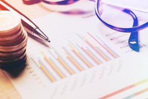 Summary report and financial analyzing concept, Pen and notebook with thailand coin and eyeglasses on paper report. photo