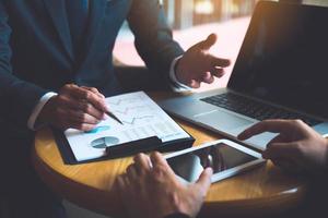 Two businessmen are discussing and analyzing the performance of the company business paper and looking for numerical data via tablets. photo