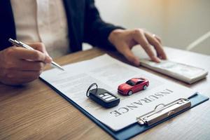 Agent is signing the insurance contract for the car at the document on the desk. photo