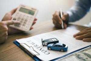 Finance manager of the car showroom is calculating the cost of reserving a new car for the customer while signing a car purchase contract. photo