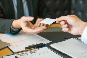 manos de dos empresarios sentados en la oficina dando y tomando tarjetas de visita vacías. foto