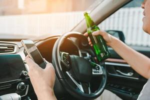 Asian men drink alcohol in the car and using mobile phones while driving. photo