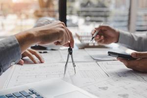 Architect working on blueprint in workplace with partnership and drawing compass. photo