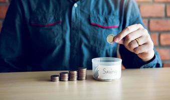 los hombres sostienen monedas que caen en la caja de dinero con el concepto de ahorro. foto