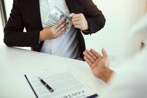 Businessman putting stack of money bills in his suit coat pocket. photo