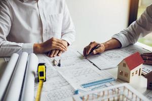 Architects engineer working with blueprints on table and discussing project together at the meeting in the office. photo