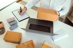 Business owner is checking the product that the customer orders the product pack in the notebook. photo