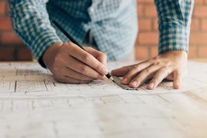 Close up hand engineering man standing examining working on a blueprint for new project in home office. photo
