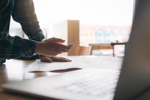 Architect standing typing on smartphone and working in modern office. photo