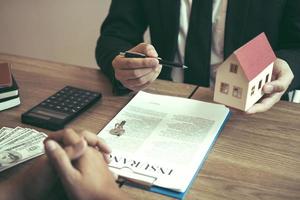 Business people home sales broker is using a pen pointing to the house model and describing the various components of the house. photo