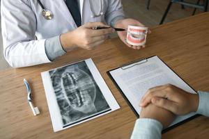 Asian dentist holding pen pointing to the dentures and is describing the problem of teeth. photo