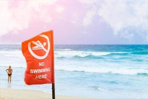 No swimming danger sign at the beach, warning sign at the beach with people swim, caution no swimming allowed. photo