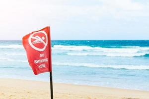 No swimming danger sign at the beach, warning sign at the beach with people swim, caution no swimming allowed. photo
