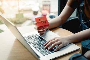 Young asian woman hand holding red gift box with shopping online concept. photo