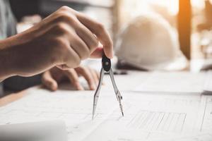 Architect working on blueprint in workplace with partnership and drawing compass. photo