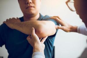 Physical therapists are checking patients elbows at the clinic office room. photo