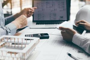 Two engineering working together and using digital tablet looking blueprint and analysis with architectural plan on desk. photo