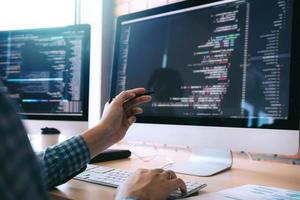 Software developer holds the pen pointing to the computer screen and is analyzing the code. photo