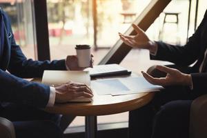 Two business partnership coworkers analysis cost work progress and gesturing with discussing a financial planning graph and company financial during a budget meeting in office room. photo