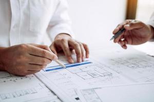 Architects or engineering working with blueprints and discussing project together at the meeting in the office. photo