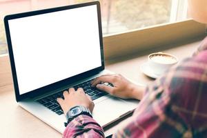 Hipster young man pressing on keyboard laptop playing for something with blank screen. photo