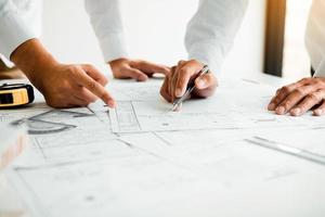 Architects or engineering working with blueprints and discussing project together at the meeting in the office. photo