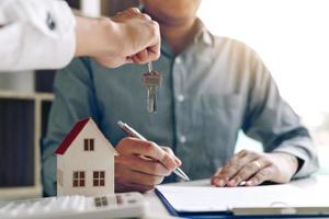 Home agents are handing out keys to home buyers who are signing contracts at the office. photo