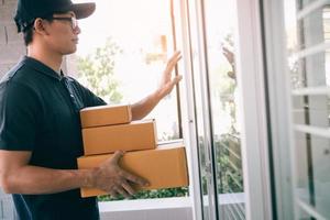 Young asian courier is using the hand of the knock at the door to deliver the goods. photo