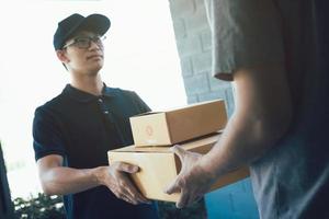 Asian cargo carrier holds a cardboard box with the package inside and the recipient is signing the package. photo