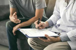 Doctor is recording the patient's information while the patient is explaining. photo