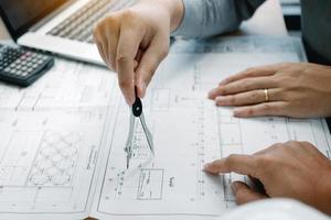 Architect working on blueprint in workplace with partnership and drawing compass. photo
