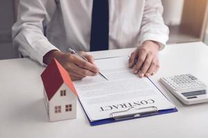 New home buyers are signing a home purchase contract at the agent's desk. photo