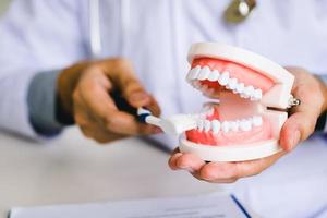 Los dentistas de mano de cerca están demostrando cómo cepillarse los dientes correctamente.