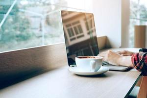 Young asian man working on laptop in cafe and drinking coffee in morning. photo