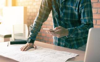Architect standing typing on smartphone and working in modern office. photo