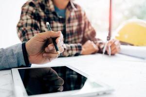 Male engineering using digital tablet with architectural plan on desk. photo