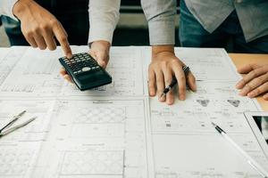 Architects or engineering working with blueprints and discussing project together at the meeting in the office. photo
