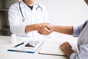 Doctor shaking hands with older patient in the clinic room. photo