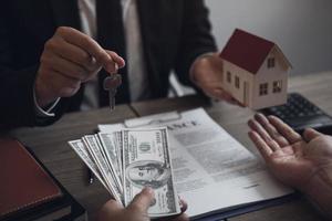 Businessman handed the house model and new homeowner giving money to real estate trading. photo