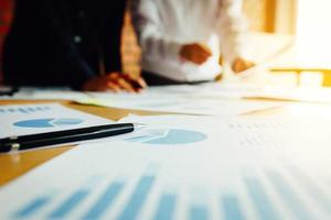 Summary report graph and two businessmen in a meeting and standing at boardroom table background. photo