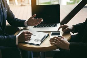 Two businessmen are discussing and analyzing the performance of the company business paper and looking for numerical data via tablets. photo