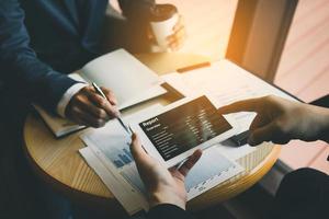 Business partnership coworkers using a tablet to chart company financial statements report and profits work progress and planning in office room. photo