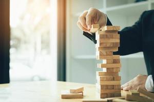 mano del hombre de negocios jugando al juego de pilas de bloques de madera con la estrategia de planificación de la gestión de proyectos. foto